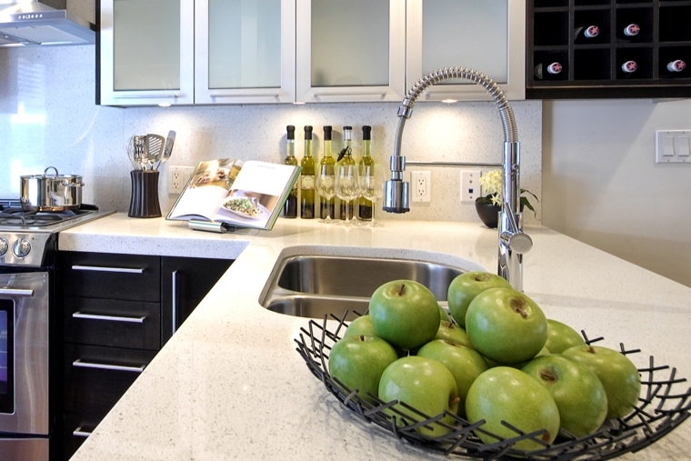 Staged kitchen with immaculate countertops and a basket of green apples.