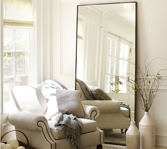 A leaning floor mirror will seemingly add extra dimension to a room. Be sure to secure a heavy floor mirror to the wall.