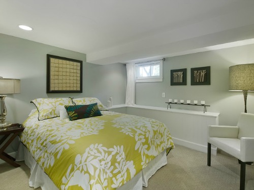 Basement bedroom in pale colors and good lighting keeps it from being too dark.