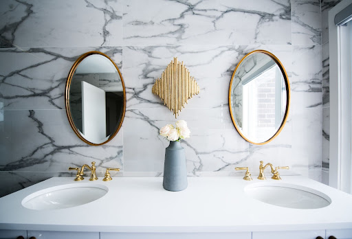 Remodeled bathroom with marble tiled wall and gold accents.