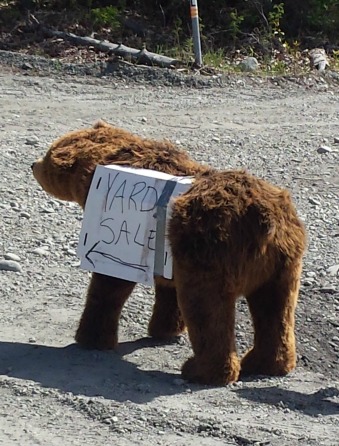 Large stuffed brown bear wearing a yard sale sign.